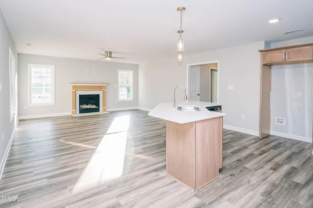 a hall with kitchen island a sink wooden floor and a fireplace