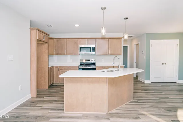 a kitchen with kitchen island stainless steel appliances a stove a sink and a wooden floor