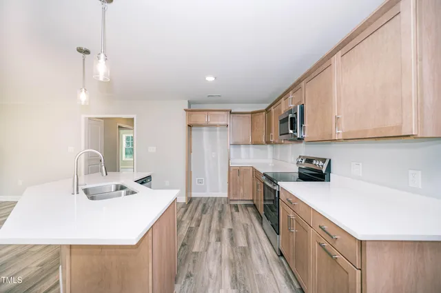 a kitchen with stainless steel appliances a sink a stove a refrigerator cabinets and a window