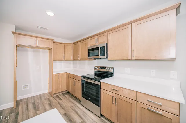 a kitchen with stainless steel appliances granite countertop white cabinets a sink a stove a refrigerator and white cabinets