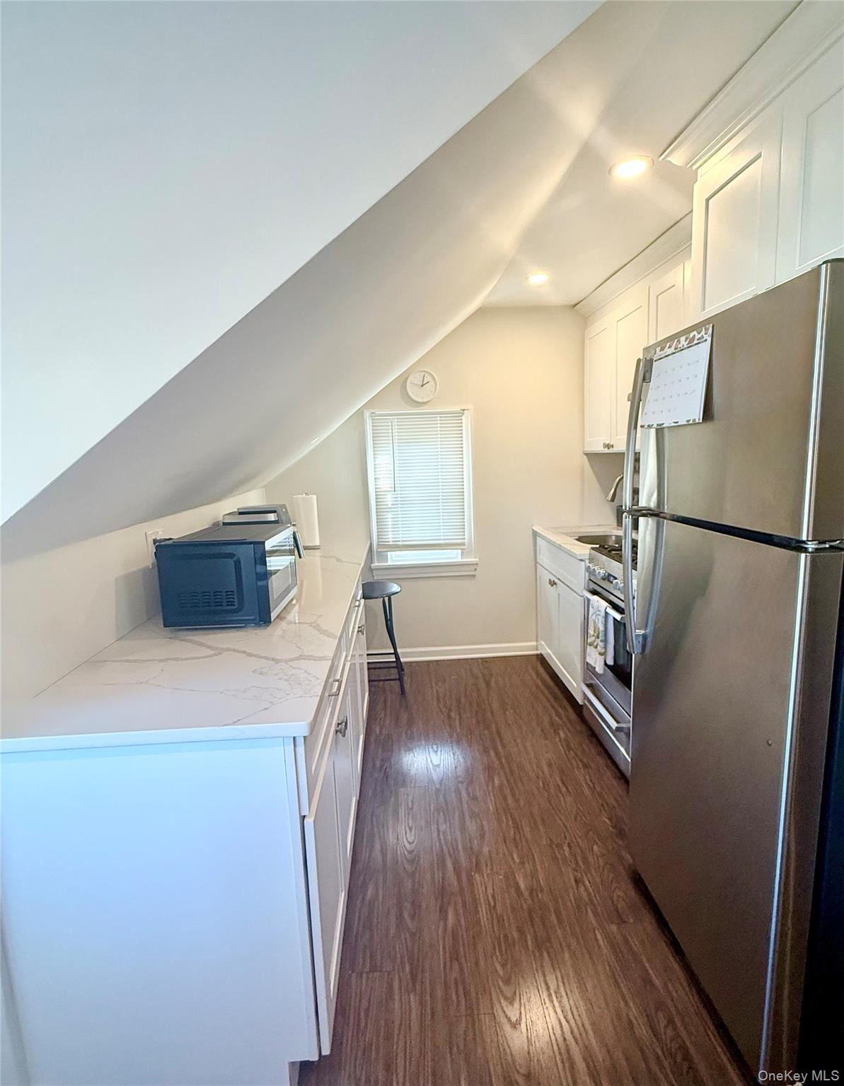 130 Clinton Avenue, Unit 3 New Rochelle, NY 10801 - Photo 4 of 10 Featuring stainless steel appliances, vaulted ceiling, white cabinetry, dark wood- type flooring