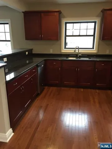 a kitchen with granite countertop wooden cabinets and a wooden floor