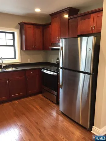 a kitchen with stainless steel appliances granite countertop a refrigerator a sink and wooden cabinets