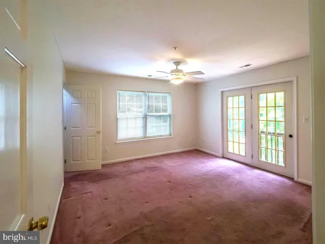 an empty room with windows and chandelier fan