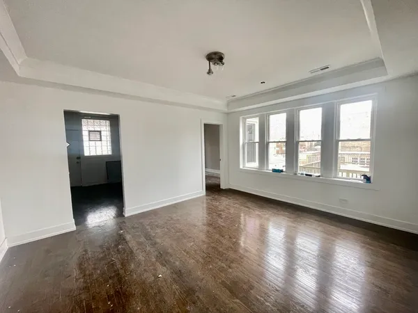 a view of an empty room with a window and wooden floor