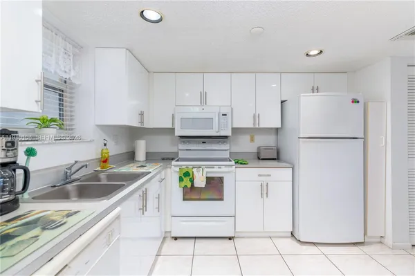 a kitchen with white cabinets and white appliances