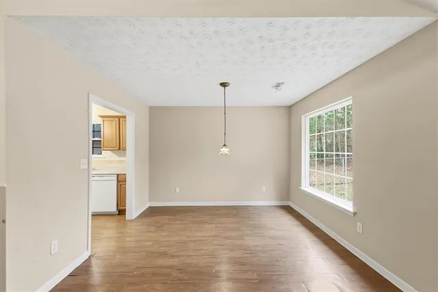 an empty room with wooden floor fireplace and windows