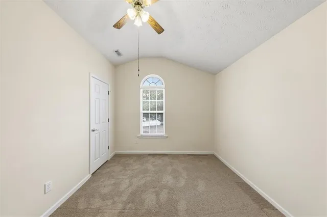 an empty room with windows and ceiling fan