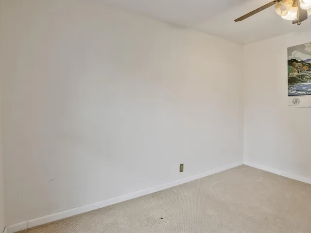 an empty room with a mirror and a fan