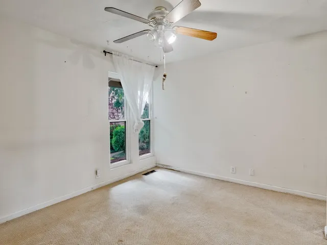a view of empty room with ceiling fan and window
