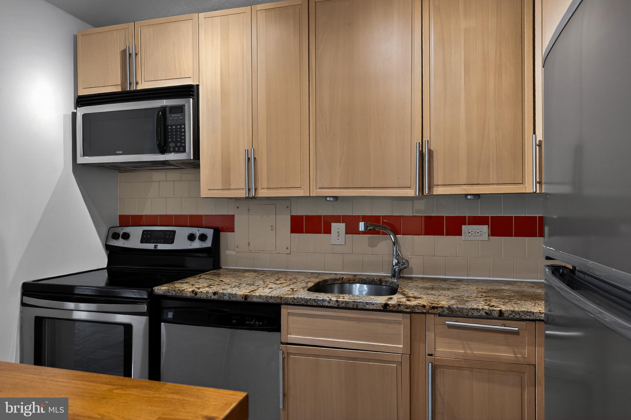 1311 Delaware Avenue Southwest, Unit S231 Washington, DC 20024 - Photo 16 of 74 a kitchen with granite countertop a stove top oven microwave and cabinets