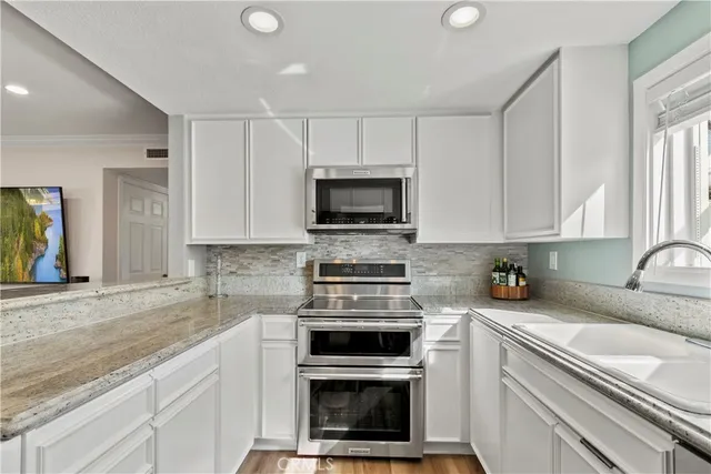 a kitchen with granite countertop a stove a sink and a microwave