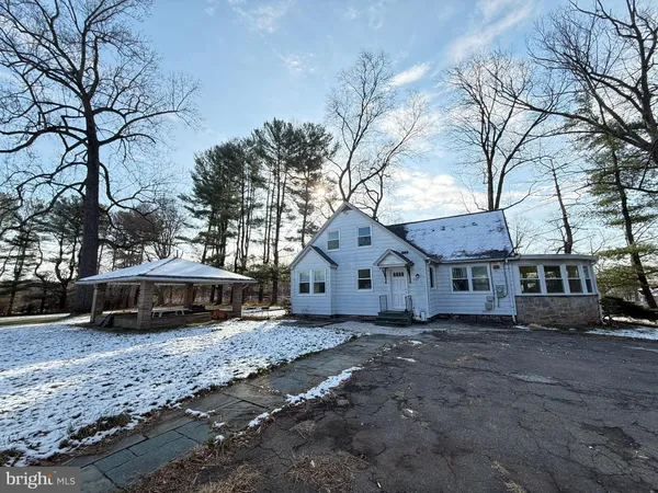 a front view of a house with a yard covered with snow and trees