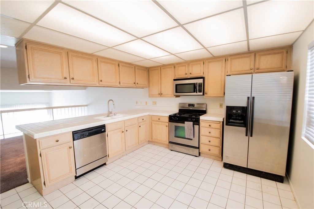 18340 Collins Street, Unit E Tarzana, CA 91356 - Photo 11 of 29 a kitchen with granite countertop white cabinets and stainless steel appliances