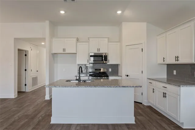 a kitchen with stainless steel appliances granite countertop a sink stove and microwave
