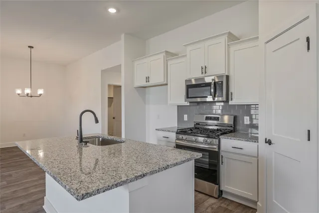 a kitchen with stainless steel appliances granite countertop a sink stove and cabinets