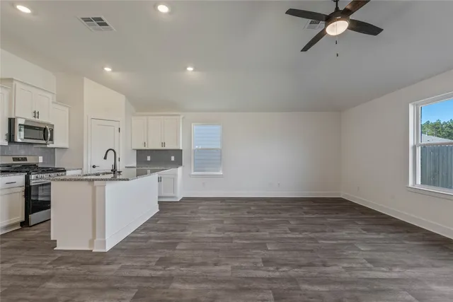 a kitchen with kitchen island granite countertop a sink appliances cabinets and wooden floor