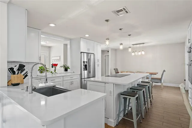 a kitchen with a sink a stove a refrigerator and white cabinets