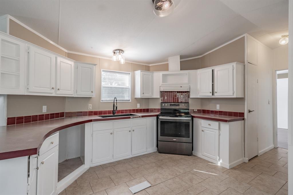 419 Wood River Road Millsap, TX 76066 - Photo 14 of 36 a kitchen with granite countertop white cabinets and stainless steel appliances