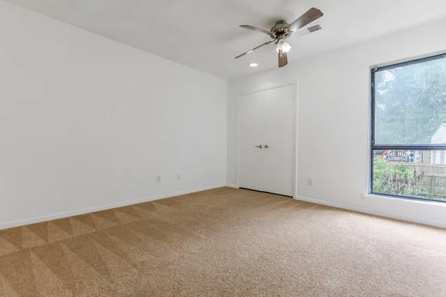 an empty room with a window and a fan