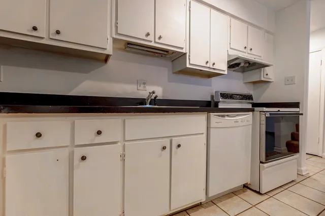 a kitchen with granite countertop white cabinets and white appliances