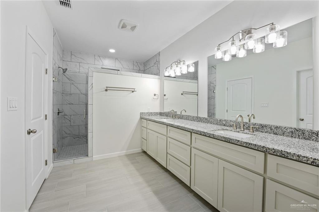 2906 Alcala Court Mission, TX 78572 - Photo 11 of 17 a bathroom with a granite countertop sink a large mirror and a shower