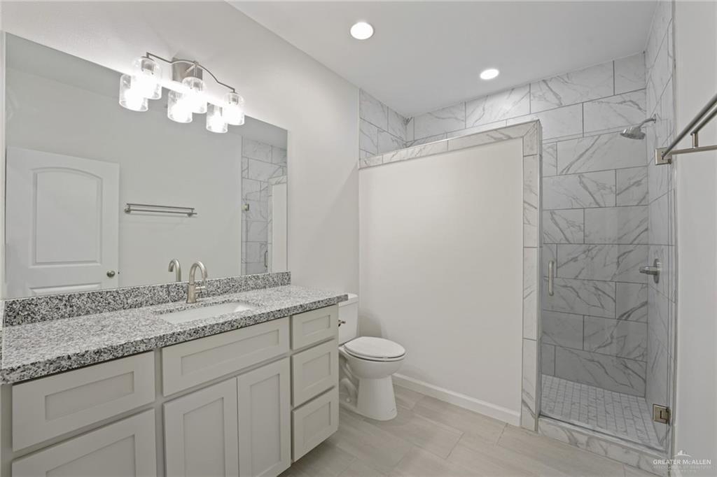 2906 Alcala Court Mission, TX 78572 - Photo 14 of 17 a bathroom with a granite countertop sink a toilet and a mirror