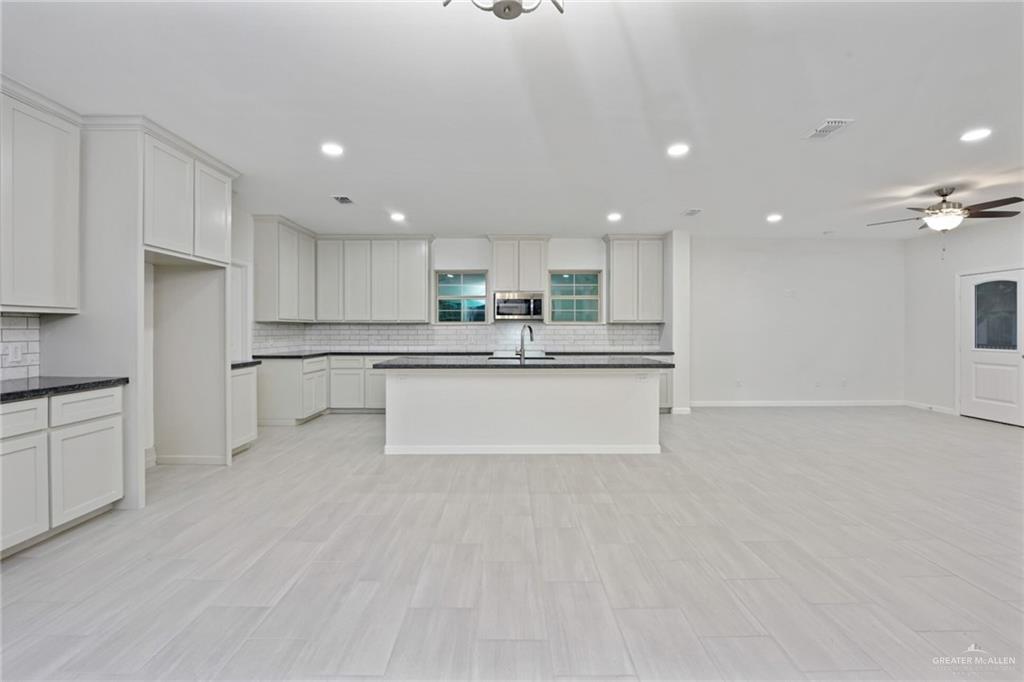 2906 Alcala Court Mission, TX 78572 - Photo 5 of 17 a large white kitchen with kitchen island a sink a stove a refrigerator and white cabinets
