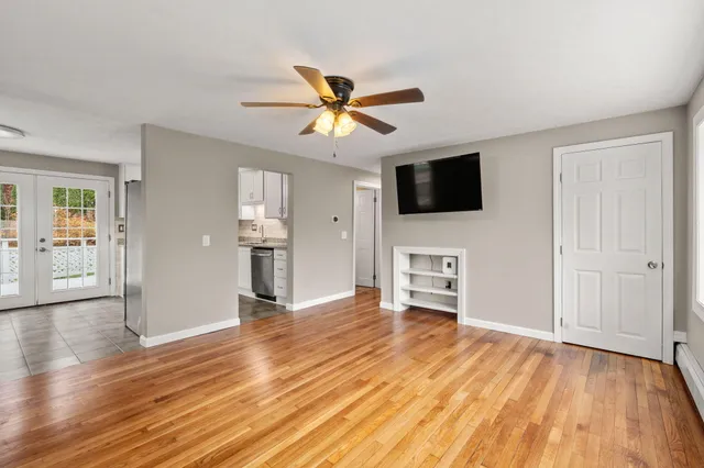 a view of a livingroom with a flat screen tv wooden floor and a ceiling fan