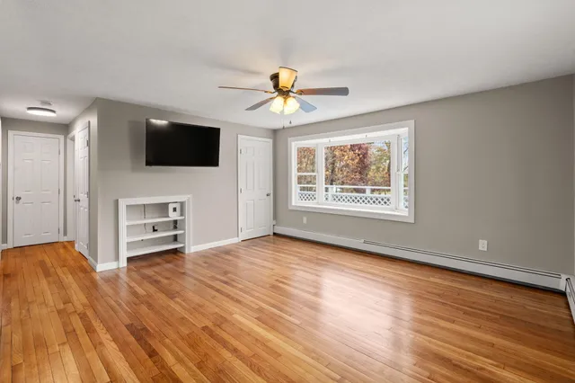 a view of a livingroom with a flat screen tv wooden floor and a ceiling fan
