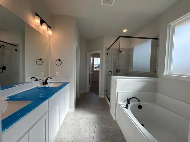 a spacious bathroom with a tub sink and mirror