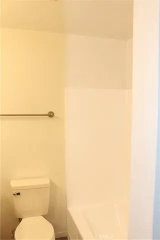 a white toilet sitting next to a white wall