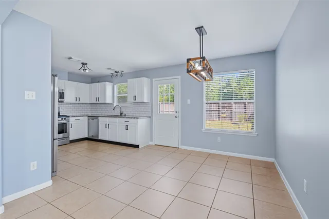 a view of a kitchen with windows and white cabinets