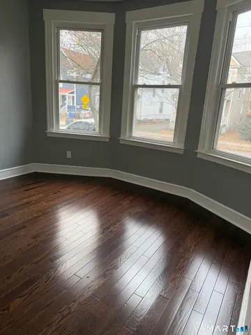 a view of an empty room wooden floor and a window