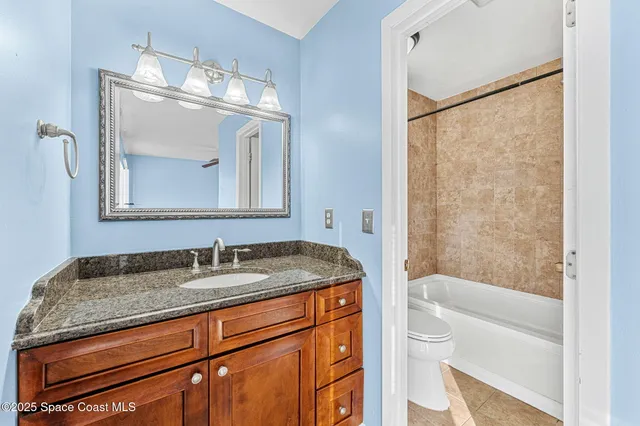 a bathroom with a granite countertop sink toilet and mirror