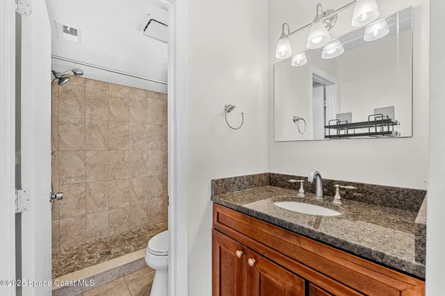 a bathroom with a granite countertop sink a toilet a mirror and shower