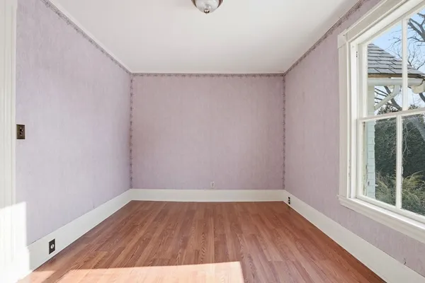 a view of an empty room with wooden floor and windows