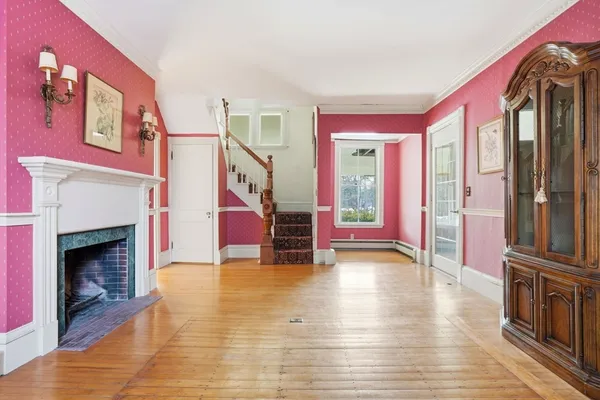 a view of a livingroom with furniture wooden floor fireplace and windows