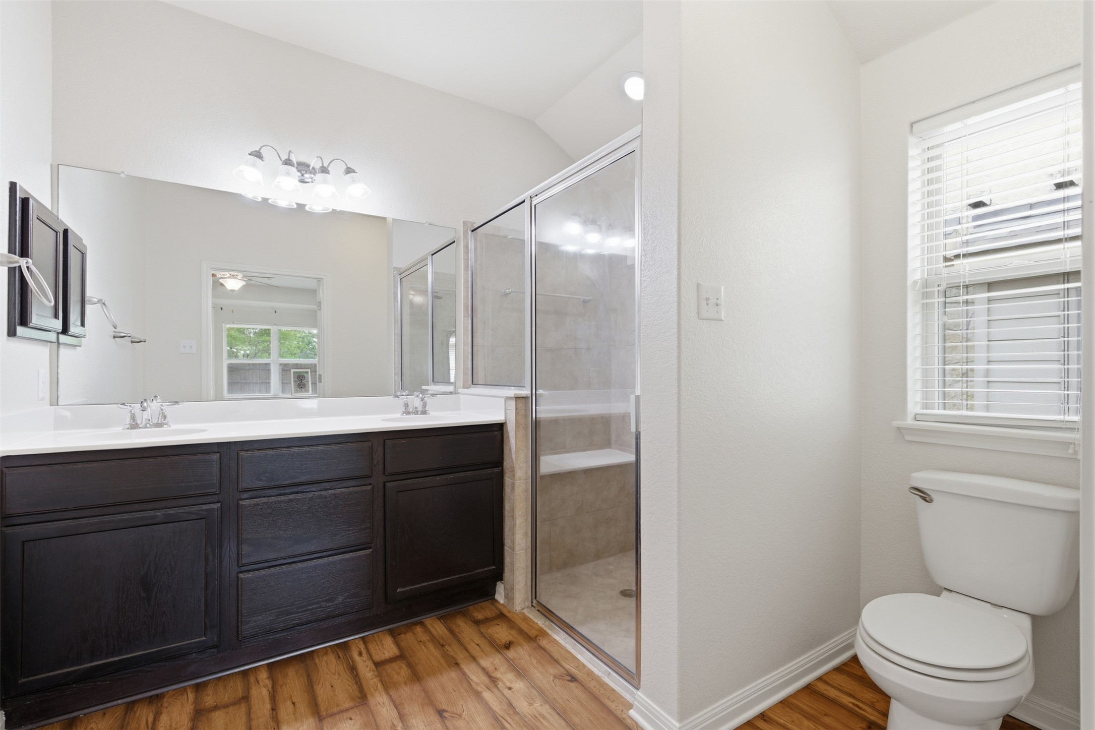 339 Sycamore Street Georgetown, TX 78633 - Photo 15 of 28 Bathroom featuring double vanity, a shower stall, light wood finished floors, a ceiling fan, and vaulted ceiling