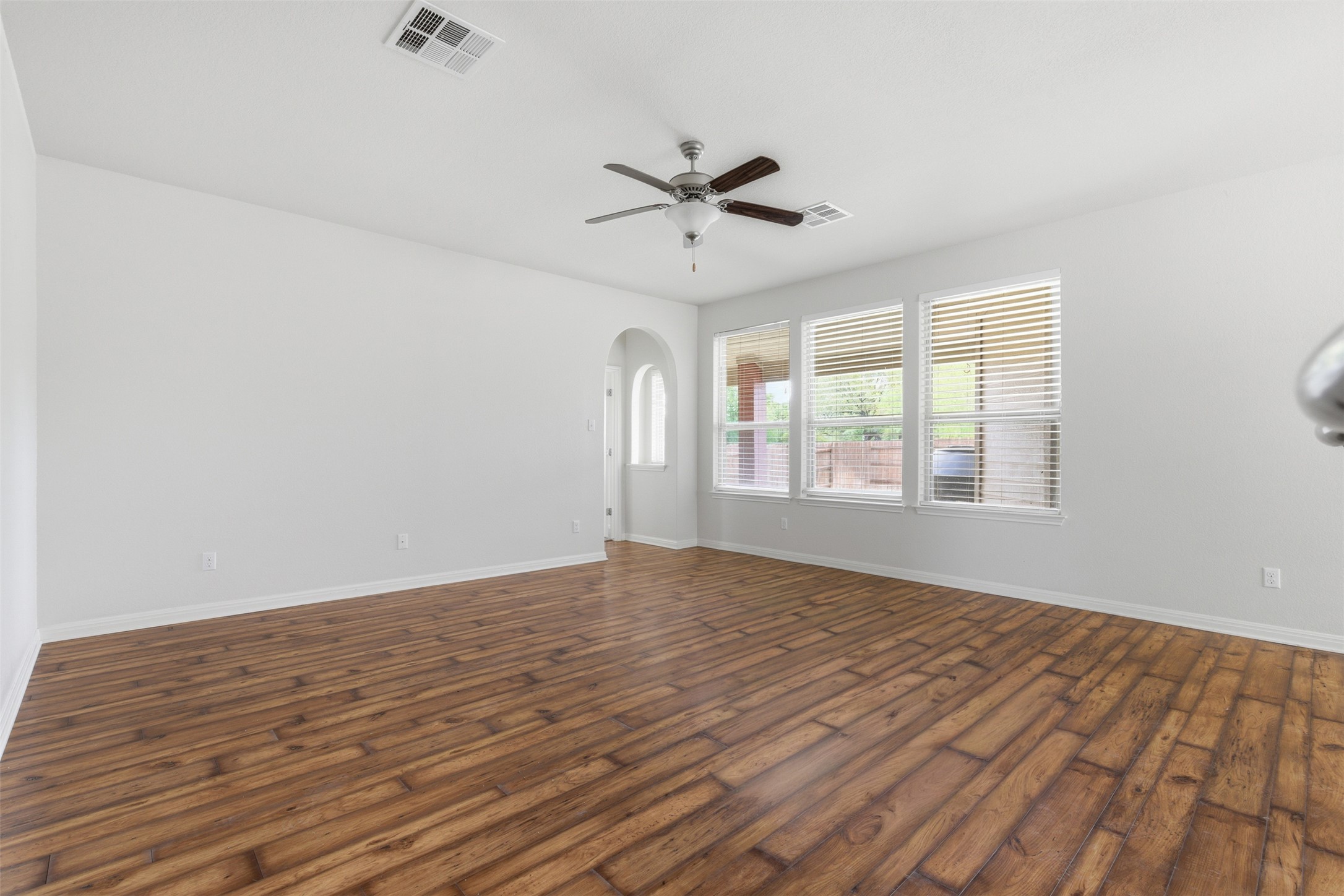 339 Sycamore Street Georgetown, TX 78633 - Photo 7 of 28 Spare room featuring arched walkways, a ceiling fan, and dark wood-type flooring