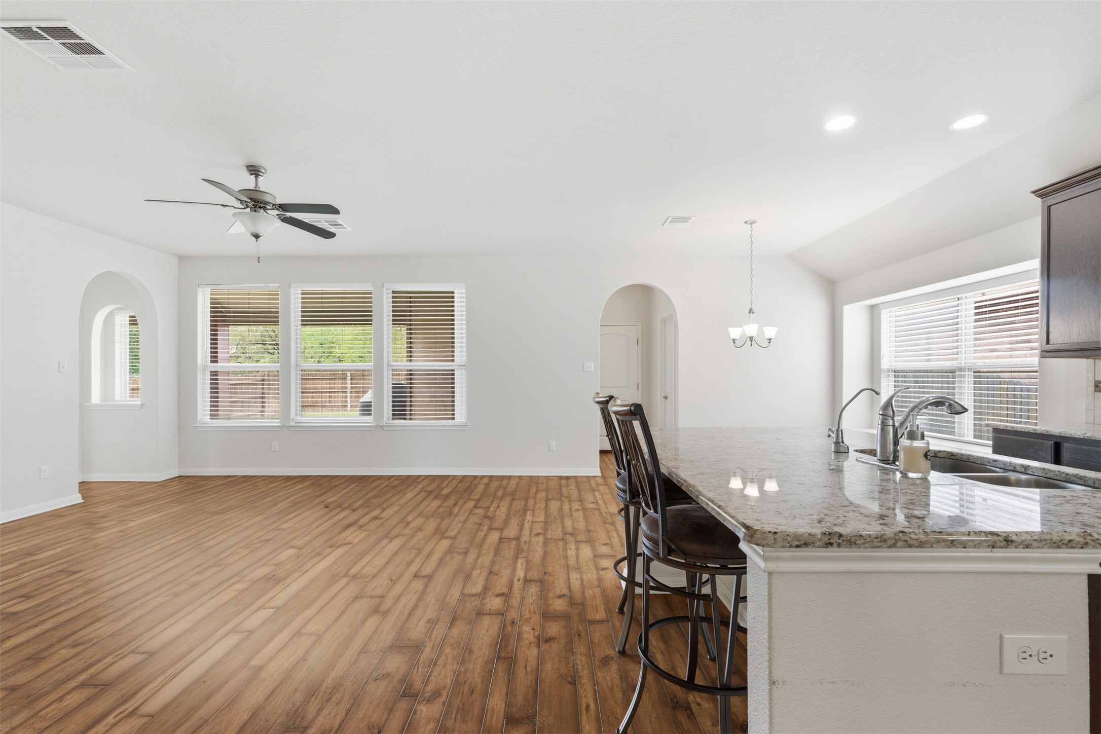 339 Sycamore Street Georgetown, TX 78633 - Photo 28 of 28 Kitchen featuring arched walkways, light stone counters, dark wood finished floors, open floor plan, and a breakfast bar