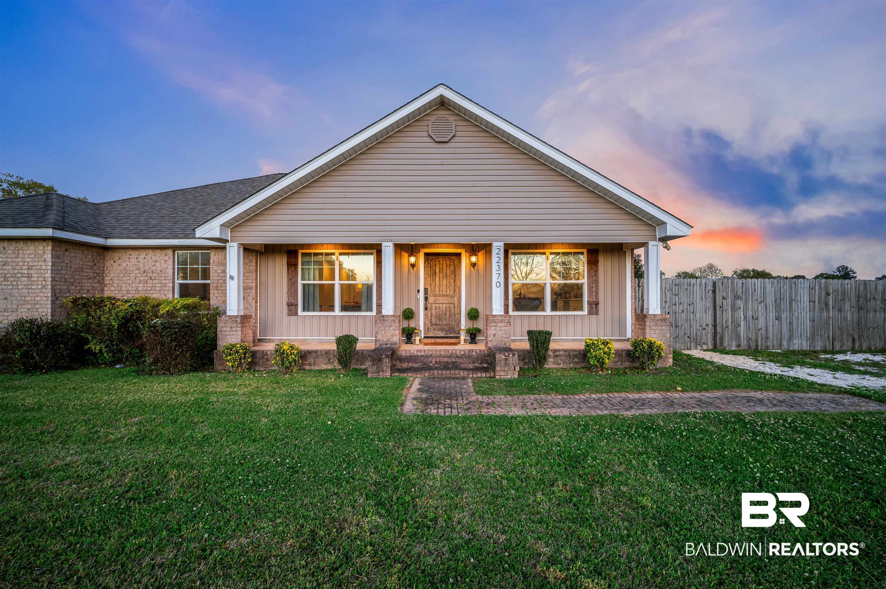 View of front of property with a lawn and fence