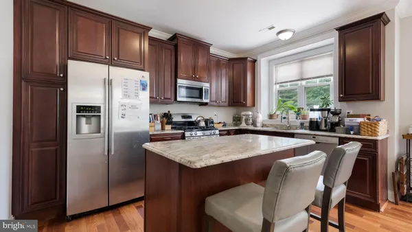 a kitchen with stainless steel appliances granite countertop a refrigerator a sink a stove a dining table and chairs