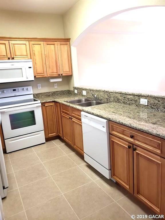 522 Northwest 39th Road, Unit 702 Gainesville, FL 32607 - Photo 8 of 15 a kitchen with stainless steel appliances granite countertop a stove a sink and a microwave