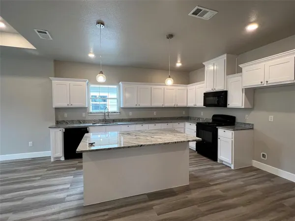 a large kitchen with stainless steel appliances granite countertop a stove a sink and a microwave