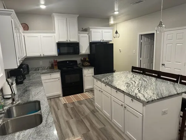 a kitchen with granite countertop a sink stove and refrigerator