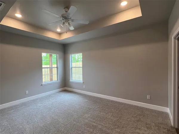 an empty room with windows and chandelier fan