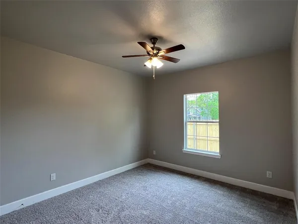 an empty room with a window and a fan