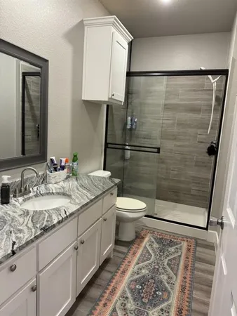 a bathroom with a granite countertop sink toilet and shower