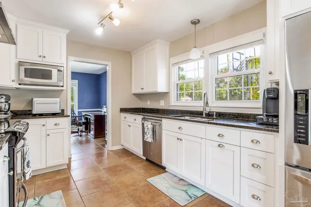 a kitchen with granite countertop a stove a sink a oven with a dining table and chairs